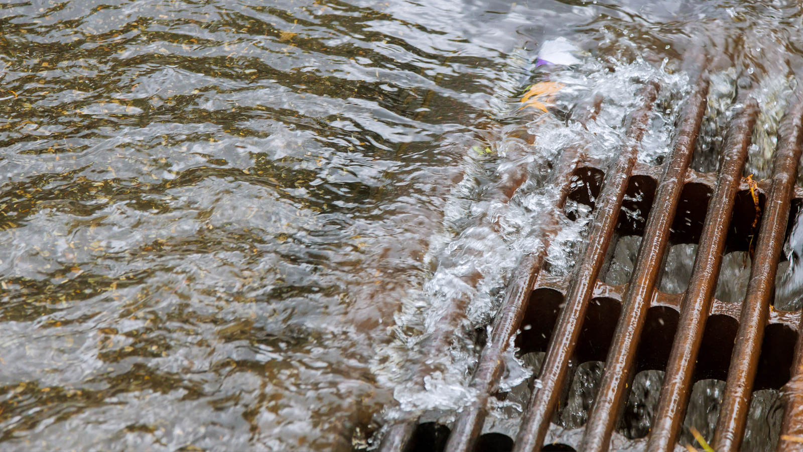 A gutter drain with water rushing into it