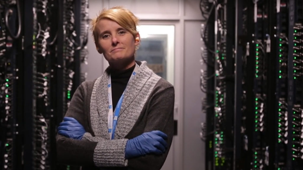 A woman standing among servers in a datacenter
